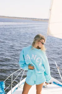 Vista detallada del conjunto de sudadera azul claro para mujer con letras FANCY en un barco.