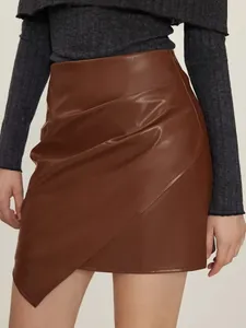 Detail of brown PU leather mini skirt featuring asymmetrical hem and pleated texture