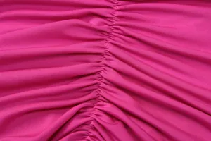 Close-up detail showing the fine texture of pink ruched fabric on a slim evening dress
