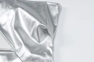 Close-up of the silver metallic PU leather fabric and stitching on a backless dress