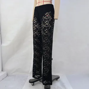 Close-up detail of the intricate black floral lace pattern on see-through trousers
