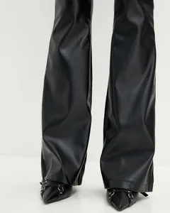 Close-up detail of black shiny PU leather flared trousers showing texture and sheen