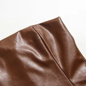 Hochwertige Nahaufnahme der braunen PU-Leder-Stofftextur eines sexy, eng anliegenden Midikleids