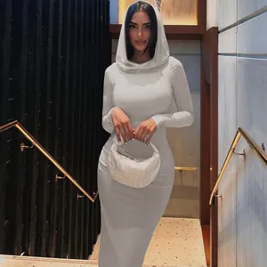 Model wearing a white long sleeve hooded bodycon maxi dress in a modern indoor setting