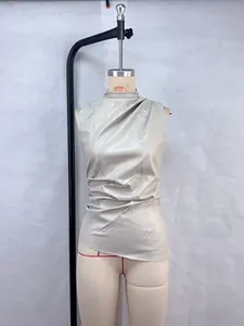 Detail of sleeveless faux leather top with high neck and asymmetrical pleated hem