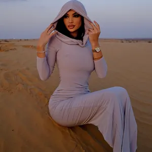 Modella che posa in abito lungo lilla con cappuccio su uno sfondo di dune del deserto