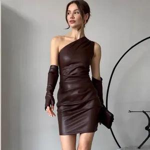 Detailopname van een stijlvolle bruine faux-leren mini-jurk met één schouder en handschoenen.