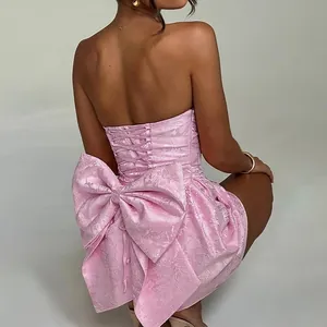 Elegant pink jacquard strapless mini dress with large back bow and lace-up detail.