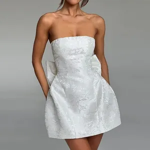 Elegant white jacquard strapless mini dress featuring a statement back bow for a chic look.
