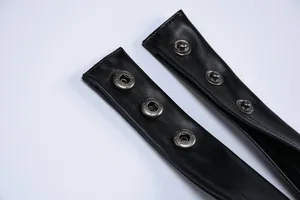Macro detail of high-quality silver snap buttons on black faux leather dress straps.