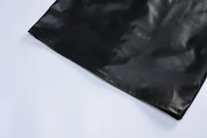 Close-up of the smooth hemline and faux leather texture of a black bodycon dress.