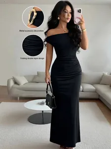 Elegant off-the-shoulder black maxi dress with folding detail and metal accessory.