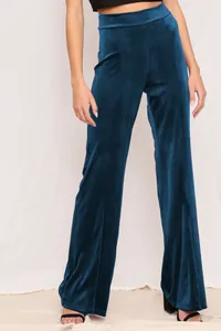 Detail showing the rich texture and high-waisted fit of dark teal velvet trousers.
