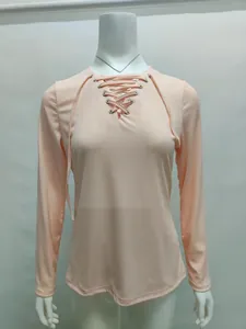 Close-up detail of a pink ribbed knit long sleeve top featuring a lace-up V-neckline