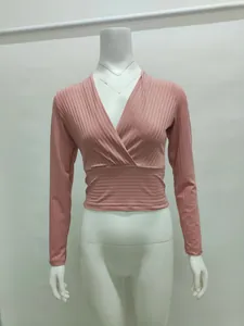 Détail d'un haut cache-cœur rose à manches longues et col en V sur un mannequin de vitrine blanc