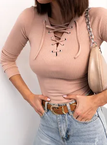 Close-up of a women's beige ribbed knit long sleeve top with a sexy lace-up V-neck design.