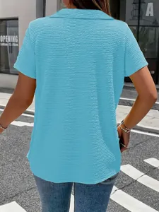 Back view of women's light blue textured short-sleeve t-shirt in an outdoor street setting