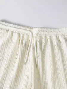 Detailansicht cremefarbener Strickshorts mit elastischem Bund und weißem Kordelzug.