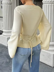Back view of light yellow long sleeve blouse with flared sleeves and tie waist