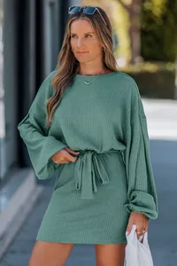 Dettaglio di un mini abito verde in maglia a coste con cintura e maniche lunghe