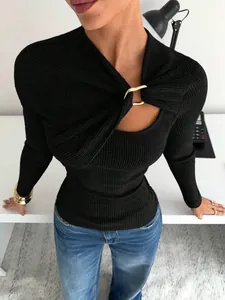 Détail d'un haut noir à manches longues avec découpe asymétrique et boucle métallique