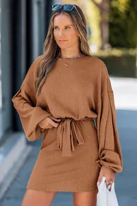 Dettaglio di un abito in maglia a coste color caramello con vita annodata e maniche a lanterna