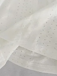 Nahaufnahme von weißer Lochstickerei und Spitzendetails an einem Sommer-Top-Stoff
