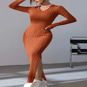 Detail van de geribbelde gebreide textuur van een oranje maxi-jurk met lange mouwen