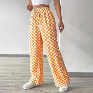 Close-up detail of stylish orange and white checkered high-waist straight-leg trousers