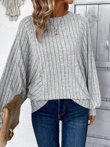 Dettaglio del maglione grigio in maglia a coste con ampie maniche a pipistrello.