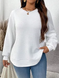 Close-up detail of white waffle texture on casual long-sleeve top with curved hem