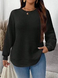 Close-up of black plus size sweatshirt with quilted grid texture and curved hem
