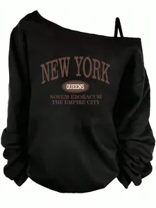 Close-up of the vintage New York Queens graphic print on an off-shoulder black sweatshirt