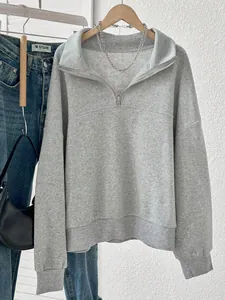 Detail view of a grey half-zip fleece sweatshirt styled with denim and accessories.