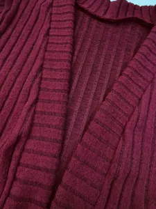 Primer plano de la textura de punto acanalado burdeos de una chaqueta tipo cárdigan.