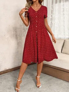 Detail view of a red V-neck dress with white heart patterns and front buttons.