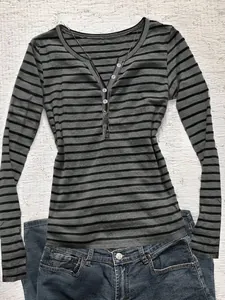 Detail of a grey striped Henley long sleeve T-shirt with white buttons on flat lay.