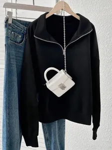 Detail shot of a black half-zip loose sweatshirt paired with a stylish white mini bag.