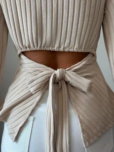 Close-up detail of the open back and tie-knot design on a beige ribbed knit top