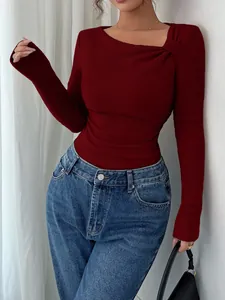 Detail of red ribbed knit top featuring asymmetrical neckline and ruched shoulder design.