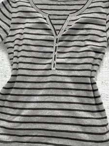 Detail view of a striped casual Henley T-shirt featuring a buttoned V-neckline for women.