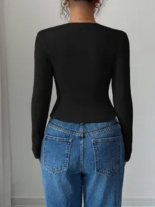 Back view of a black long-sleeved ribbed knit top styled with classic blue denim jeans