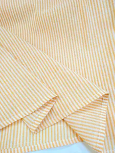 Detailed view of yellow and white vertical striped fabric texture and clean hem stitching