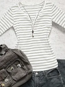 Flat lay of a striped long sleeve Henley top with a casual grey bag and denim jeans