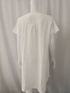 Detail of the back silhouette on a white loose cotton linen short sleeve casual dress.
