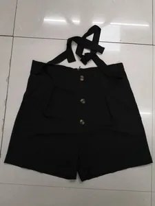 Macro detail of black high-waisted shorts featuring three front buttons and a stylish tie-waist.