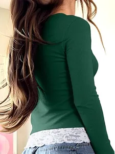 Detail view of the ribbed fabric and white lace hem on a dark green long-sleeve top