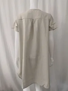 Back view of a loose minimalist beige cotton linen short-sleeved dress on a mannequin