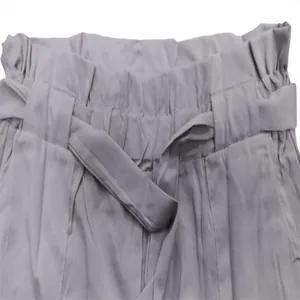 Close-up detail of grey paper-bag waist shorts featuring an elastic band and self-tie belt