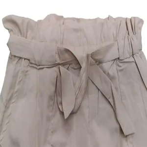 Close-up of high-waisted beige shorts with elastic paperbag waist and matching fabric belt